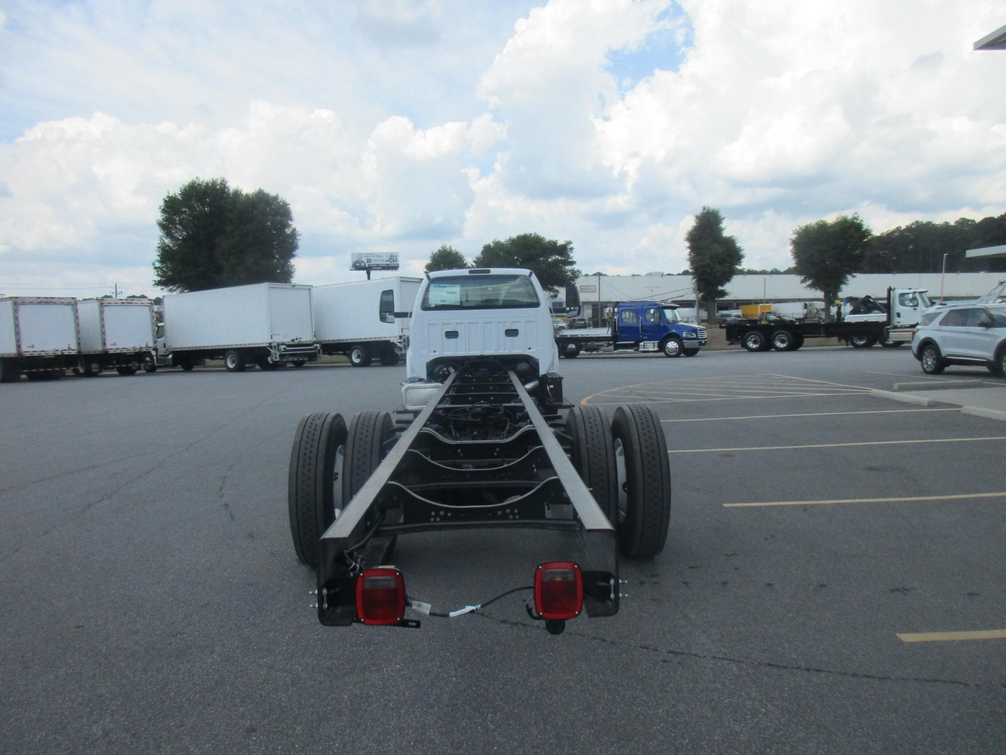 Chassis cab of a 2027 Ford F750 SD truck viewed from rear with dual rear axles, cab and chassis frame, taillights, and hitch wiring visible.