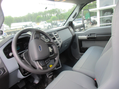 Interior of a new Ford F-750 cab and chassis showing steering wheel, dashboard, and front seats.