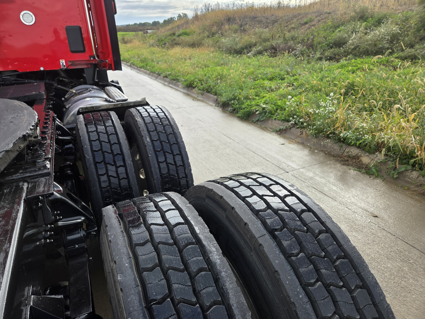 Kenworth T680 truck rear dual axle wheels and red cab visible in outdoor setting.
