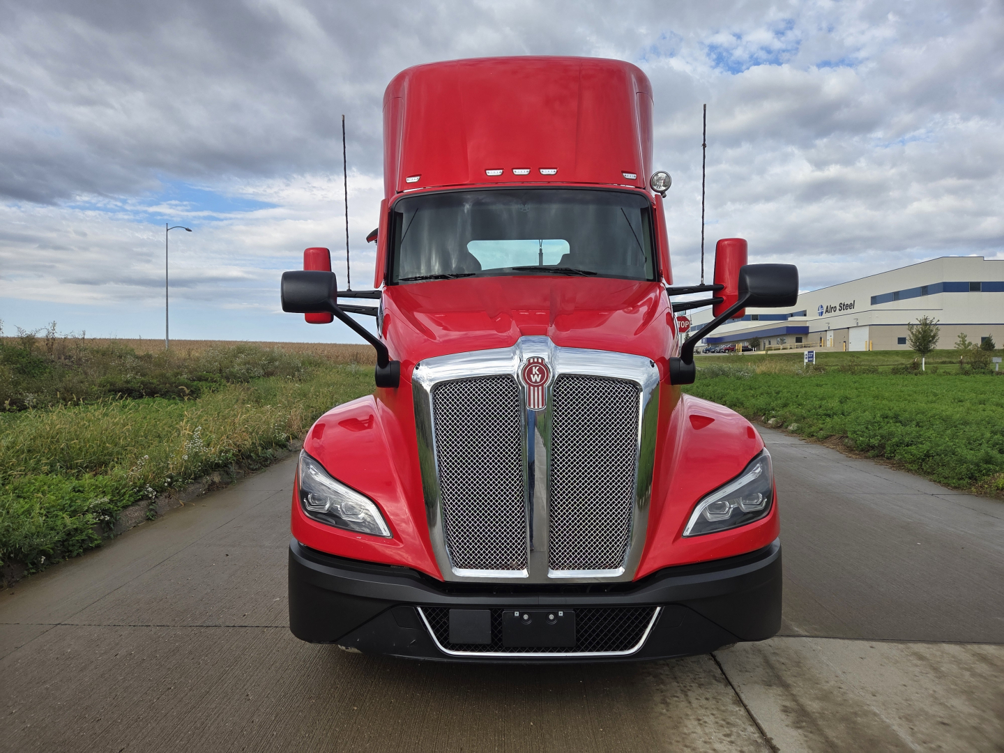Front view of a red 2023 Kenworth T680 night and day, showing bold grille, hood, headlights, mirrors, and bumper.