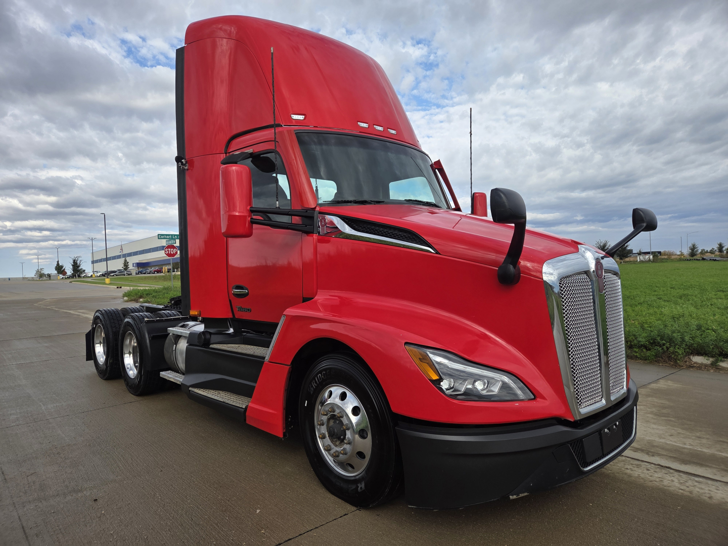Kenworth T680 tractor in red side view showing aerodynamic hood, dual 6-inch mirrors, daytime running lights, chrome grille, and truck tires. No visible VIN or text on side panels.