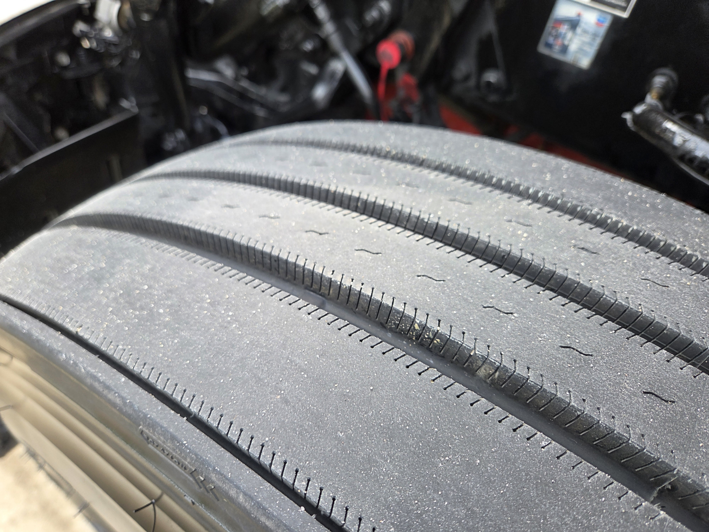 Kenworth T680 truck tire tread close-up in engine bay area, partial view of chassis and components.