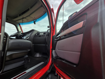 Kenworth T680 cab interior viewed from open driver door showing dashboard, steering wheel, and door panel.
