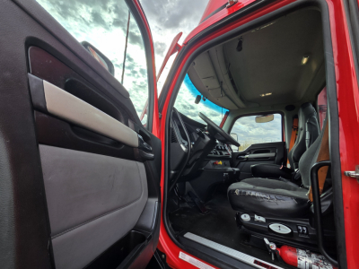 Truck interior cab with red exterior, open door revealing driver's seat and dashboard. Text visible: none clearly legible from image.