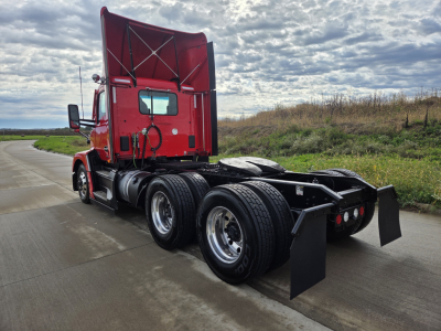 Kenworth T680 tractor with red cab, rear view showing dual rear axles and mud flaps.