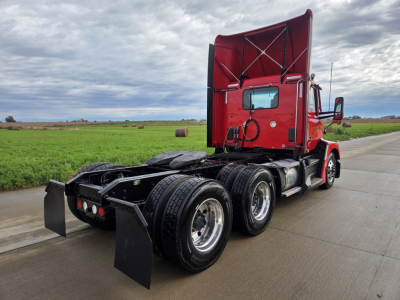 Kenworth T680 tractor rear and cab in red, showing dual rear axles and fifth wheel hitch; no visible text or labels.