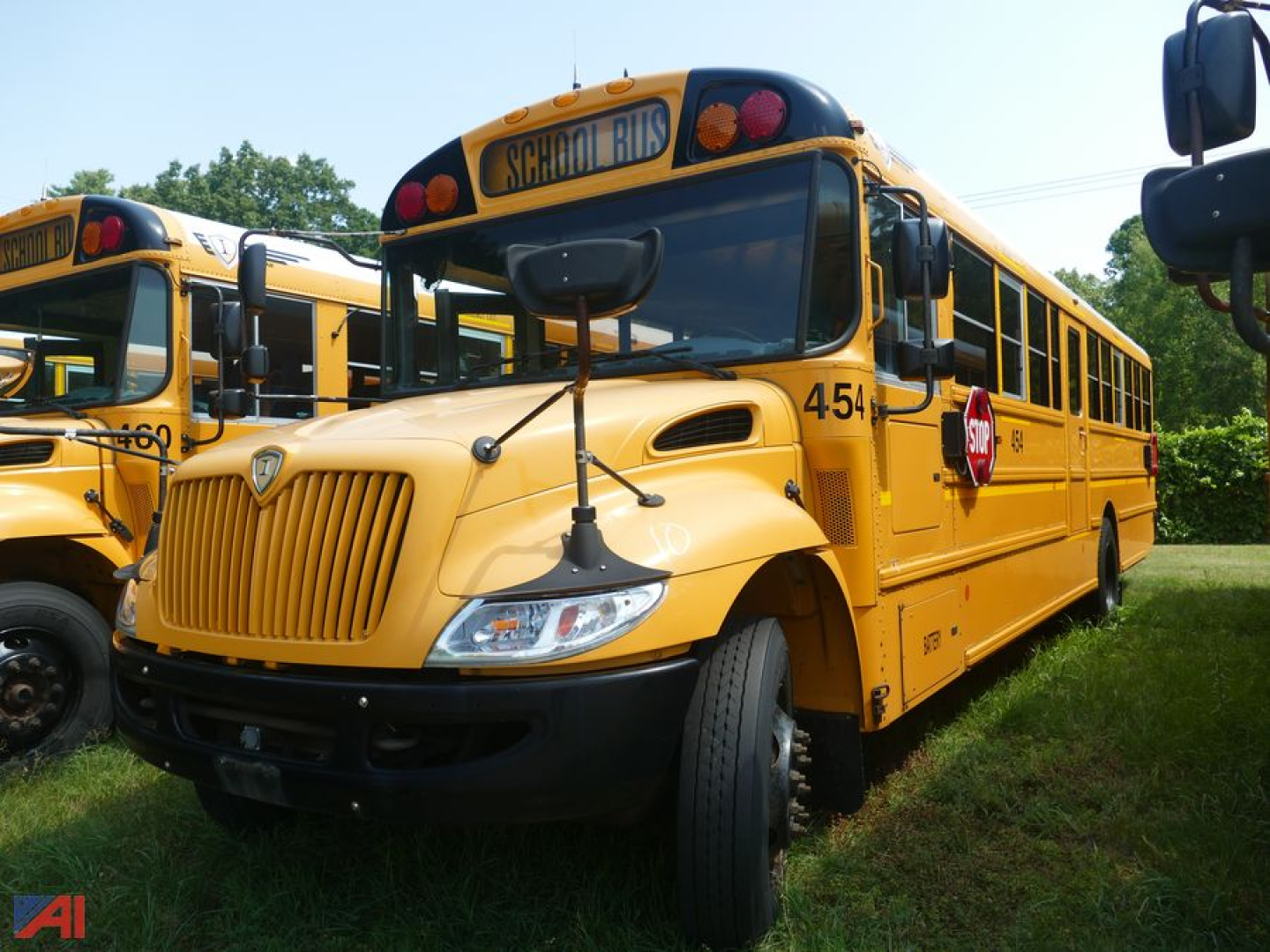 School bus with yellow body and black front grille showing 'SCHOOL BUS' sign on top and side number 454.