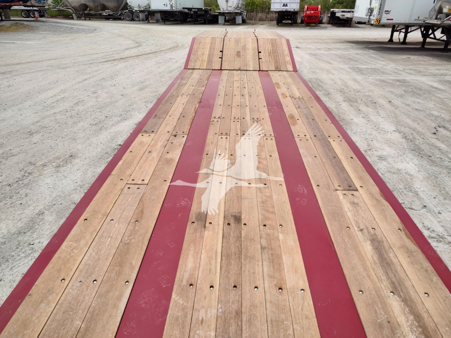 Flatbed trailer deck with wooden planks and maroon side rails; Fontaine logo on center plank.