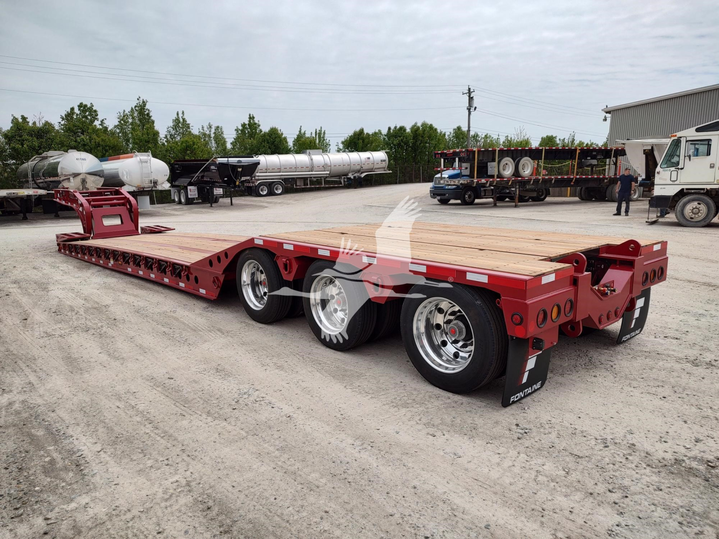 Fontaine Paver Pro lowboy trailer showing dual rear axles and red chassis with wood deck and white reflective tapes.