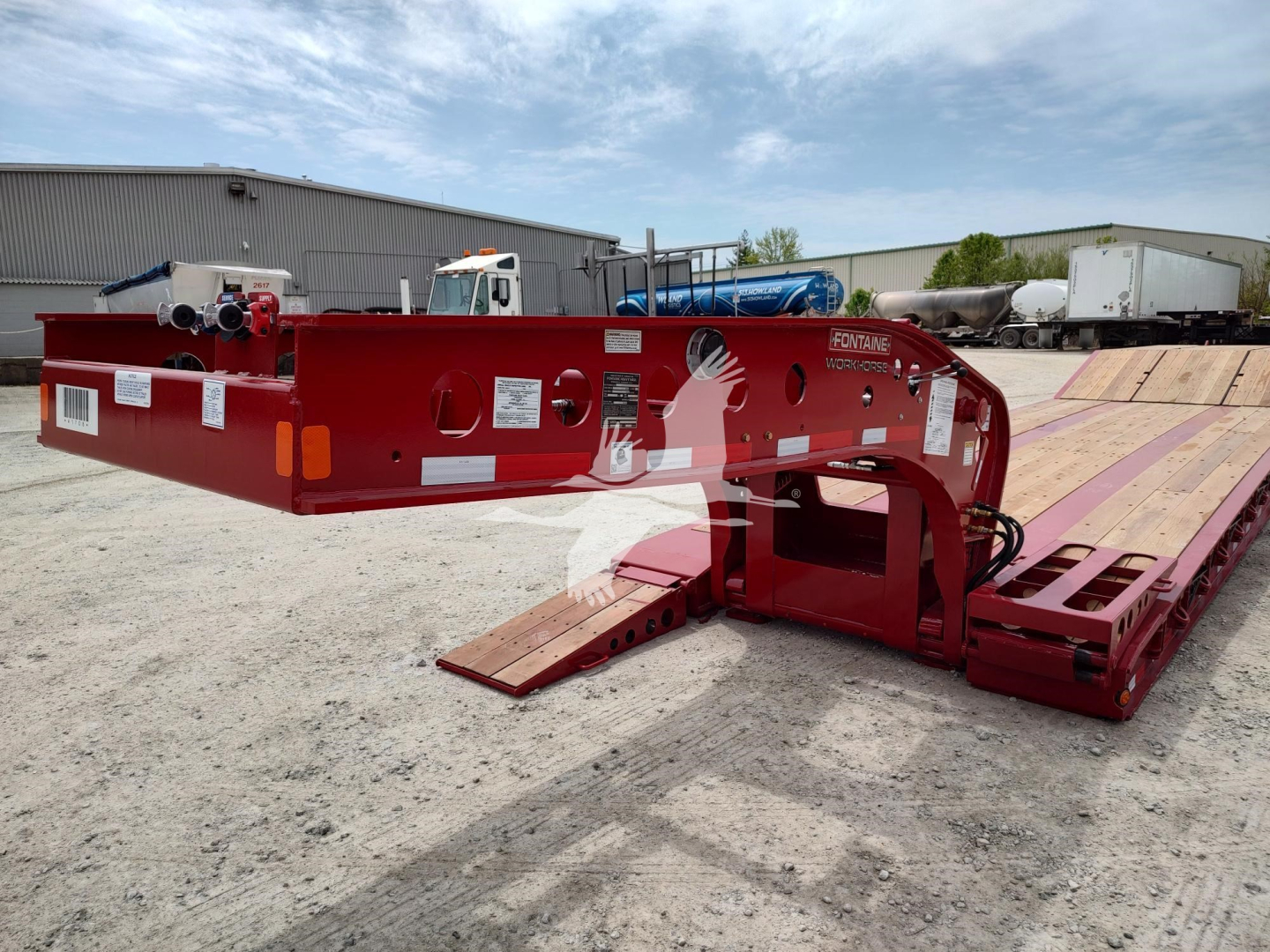 Fontaine paver pro lowboy trailer component showing red steel frame and hydraulic gooseneck with manuals and stickers visible