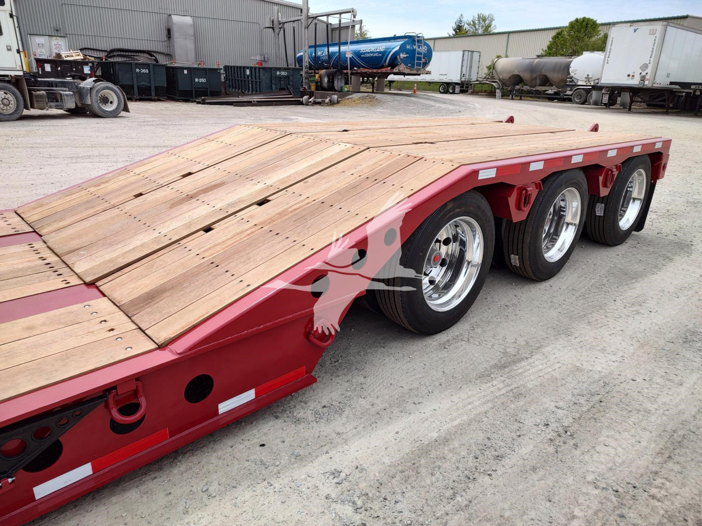 Fontaine Paver Pro lowboy trailer with triple axles and wooden deck, red frame, side rails, and chrome wheels. Visible text includes VIN and stock number stickers on the side.