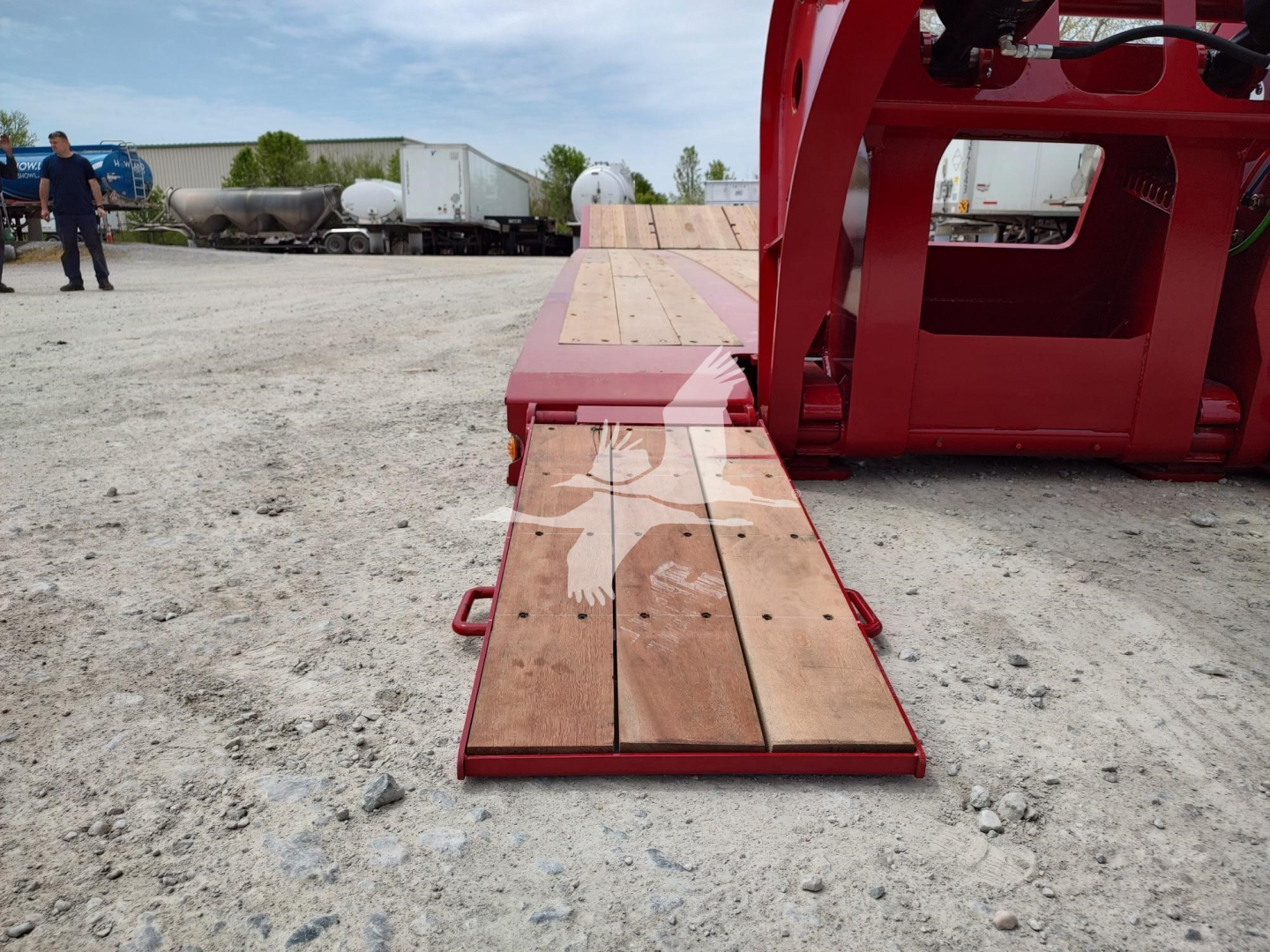 2027 Fontaine paver trailer on lowboy showing wooden deck planks and red frame in industrial lot.
