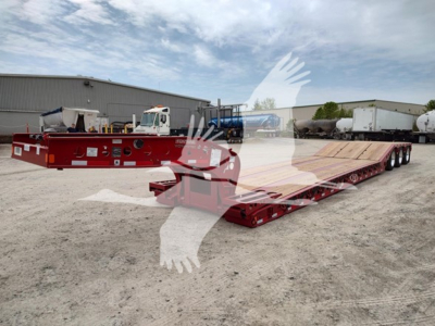 Fontaine paver trailer on a lowboy with red frame and long wooden deck, external wheelset, and front hitch in view.