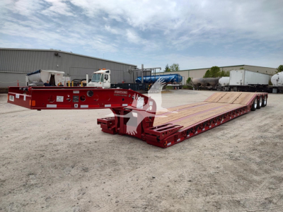 Fontaine paver lowboy trailer in red, extreme left front view with long deck and multiple axles, no visible text read clearly