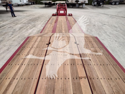 Fontaine paver Pro lowboy trailer deck showing wooden planks with red frame and ramp at end.
