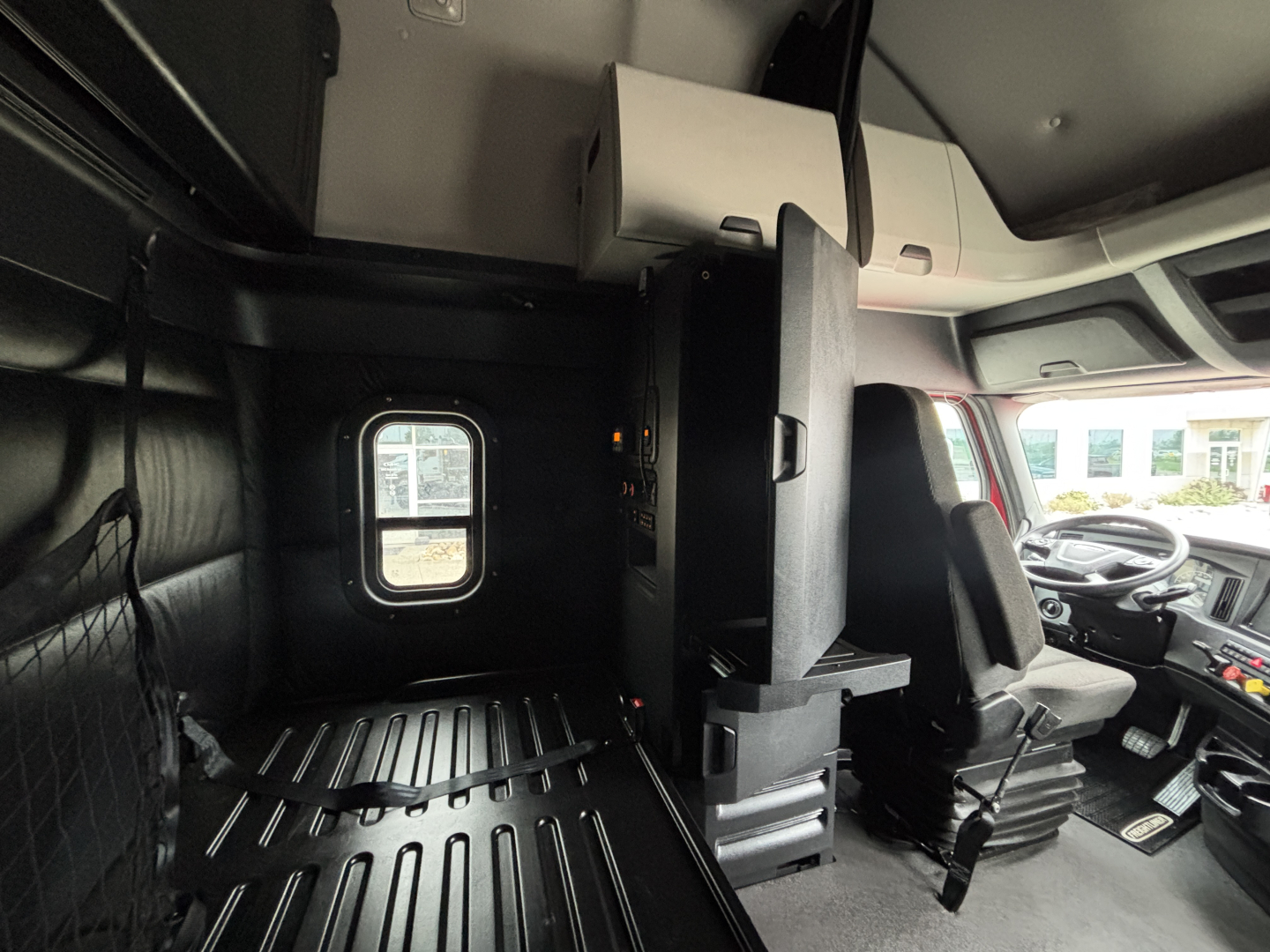 Cab interior of Freightliner PT126064ST featuring sleeper cab with bunk area, driver seat, dashboard, and partition wall.