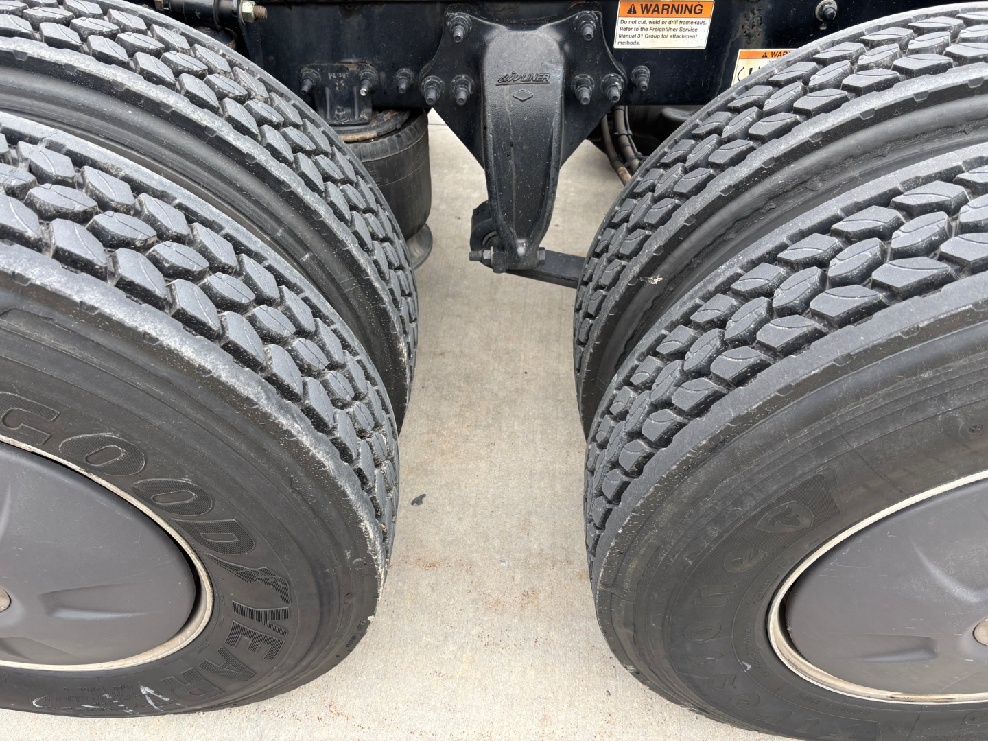 Dual rear axles with heavy tread tires and suspension components visible in a Freightliner truck chassis.