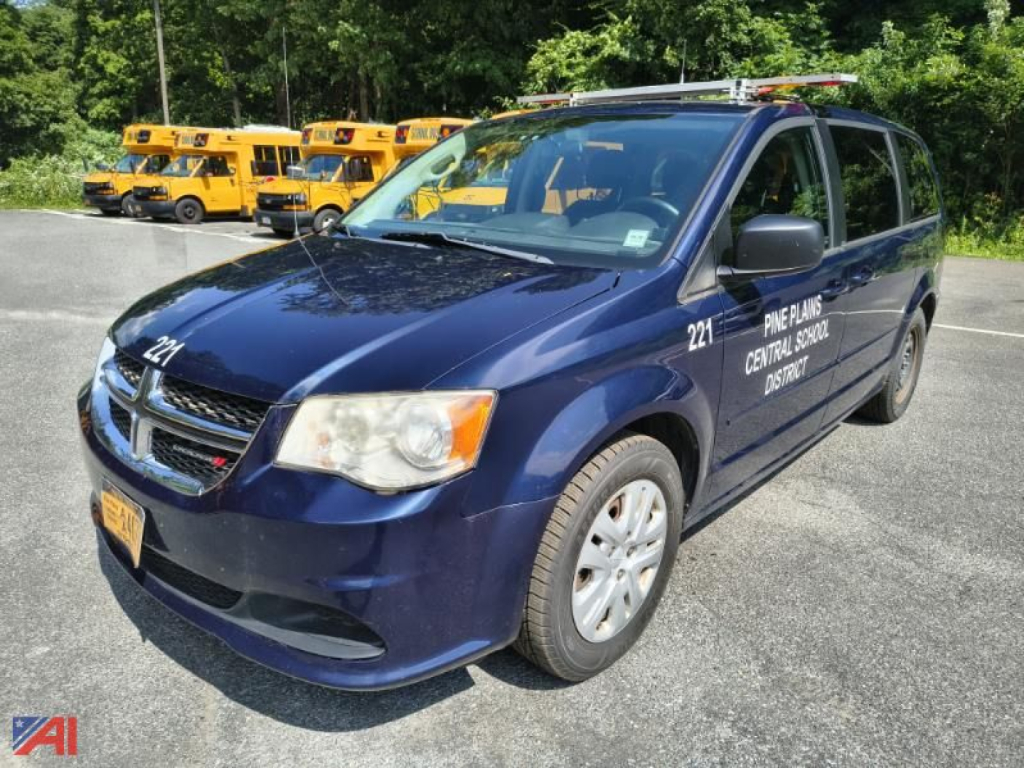Dodge Grand Caravan police or municipal vehicle with 221 numbers on front fender, dark blue color, headline text on doors, front view in a parking lot.