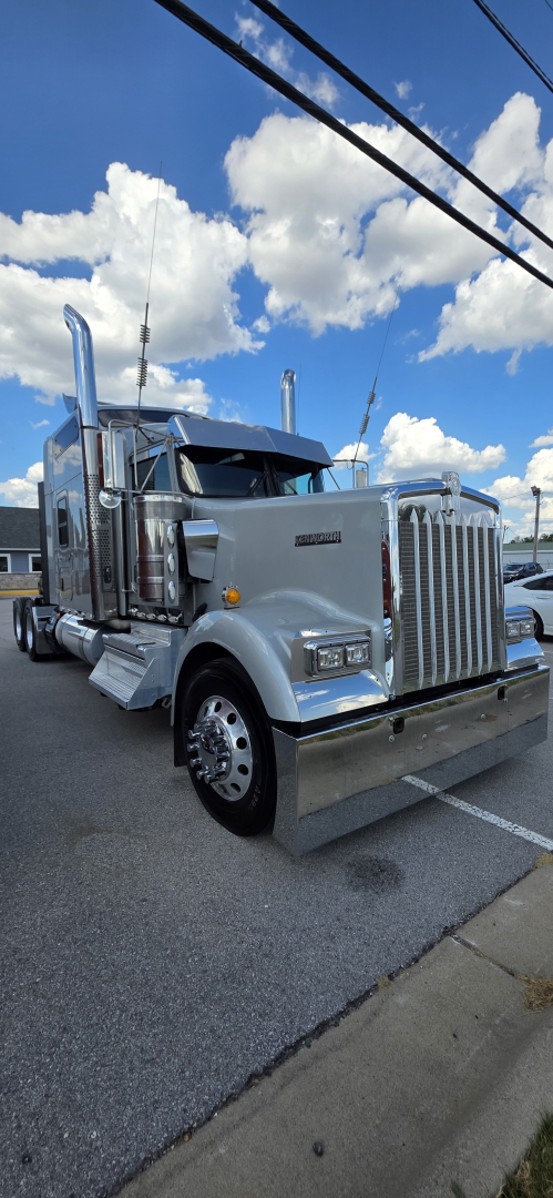 Kenworth W900 cabin chassis truck in silver showing front grille, headlights, chrome bumper, and dual air intake stacks.