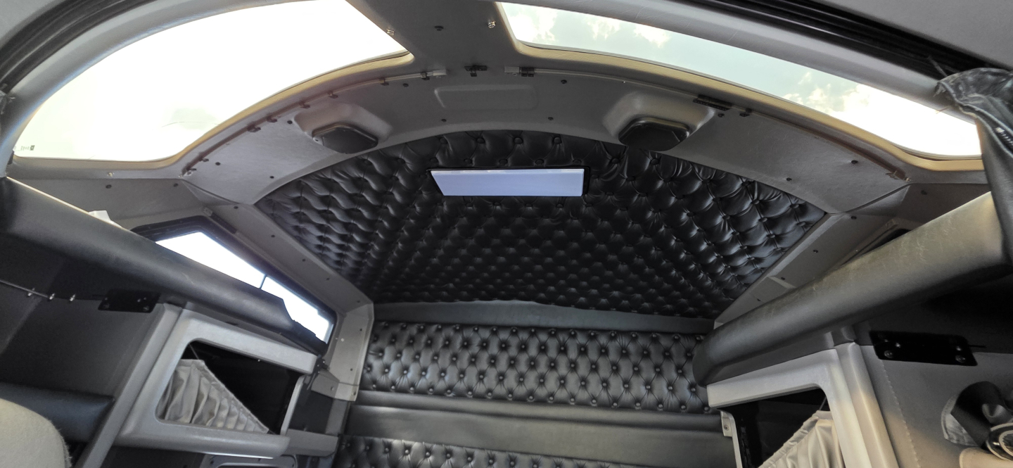 Kenworth W900 cab interior showing diamond-tufted headliner and side cabins, with storage shelves and overhead console visible.
