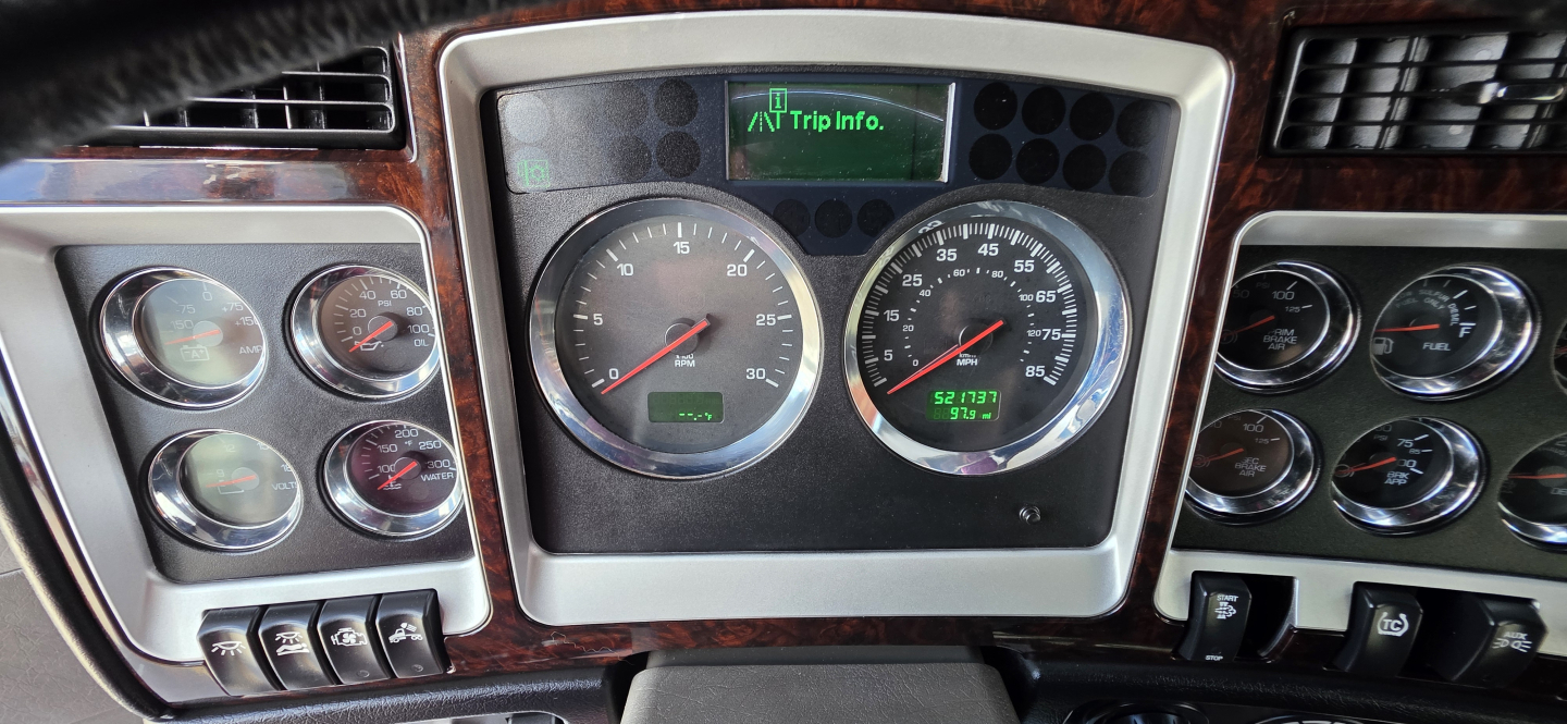 Kenworth W900 dashboard and instrument cluster in view showing gauges and center digital trip info display.