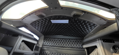 Kenworth W900 cab interior showing diamond-tufted headliner and side cabins, with storage shelves and overhead console visible.