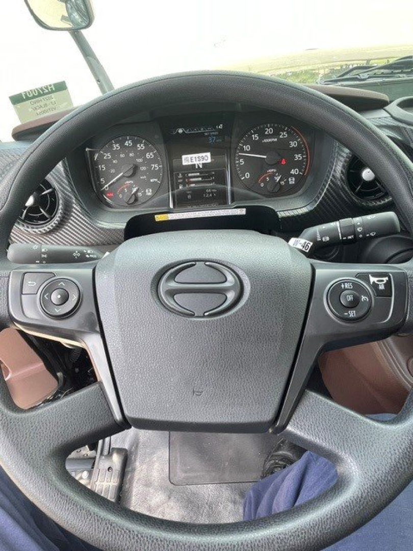 Dashboard view of a Hino L7 steering wheel with instrument cluster and stalks; no explicit model text visible beyond the Hino emblem on the steering wheel.