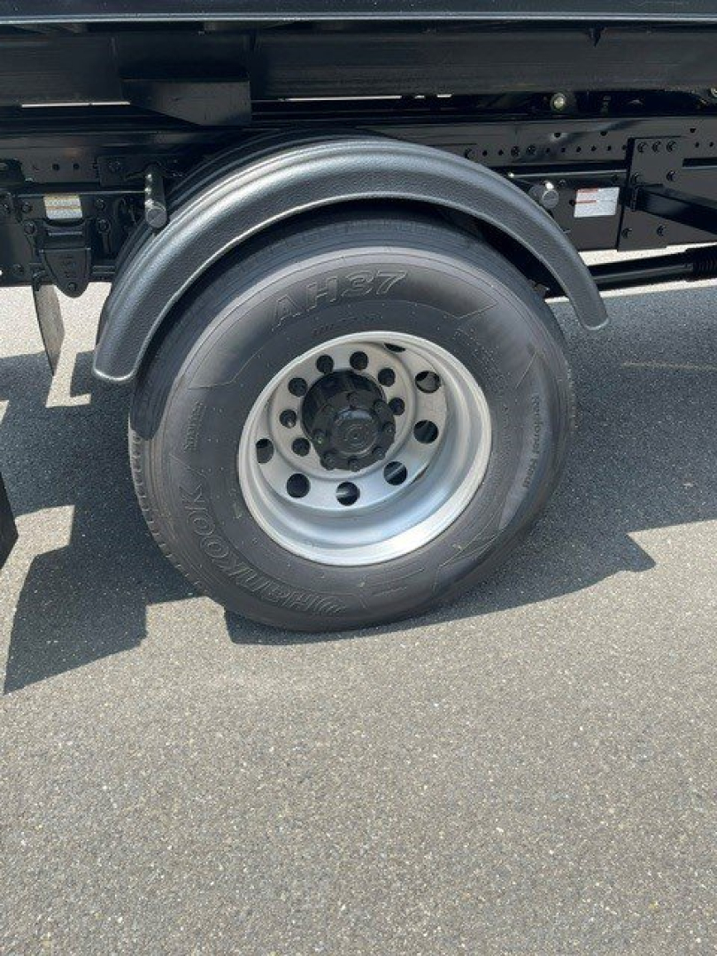 Truck wheel and fender view of a 2027 Hino L7 hooklift truck showing wheel, tire, and chassis framing.