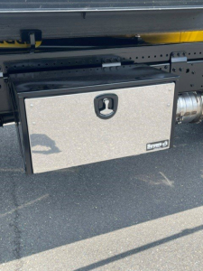 Truck side showing a metallic toolbox mounted under the chassis with a Star logo and bolts.