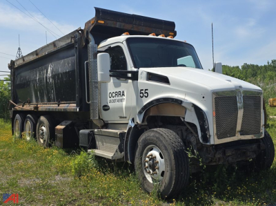 Kenworth T880 dump truck side/front view showing white cab with number 55 and black dump bed in field.