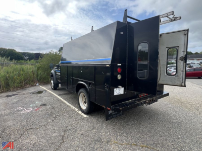 Ford F-450 utility truck rear view showing service body with side door and rear ramp, black paint, chrome bumper, and dual rear tires.