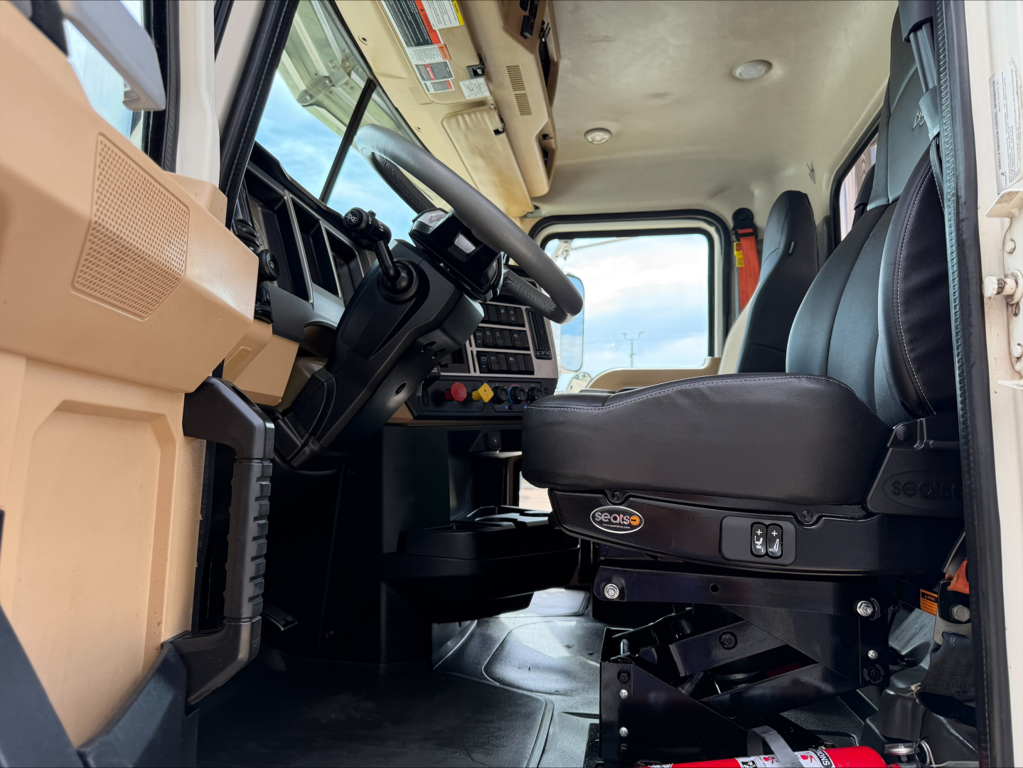 Interior view of a 2019 Mack PI64T cab with steering wheel, driver seat, dashboard, and controls visible from entry side.