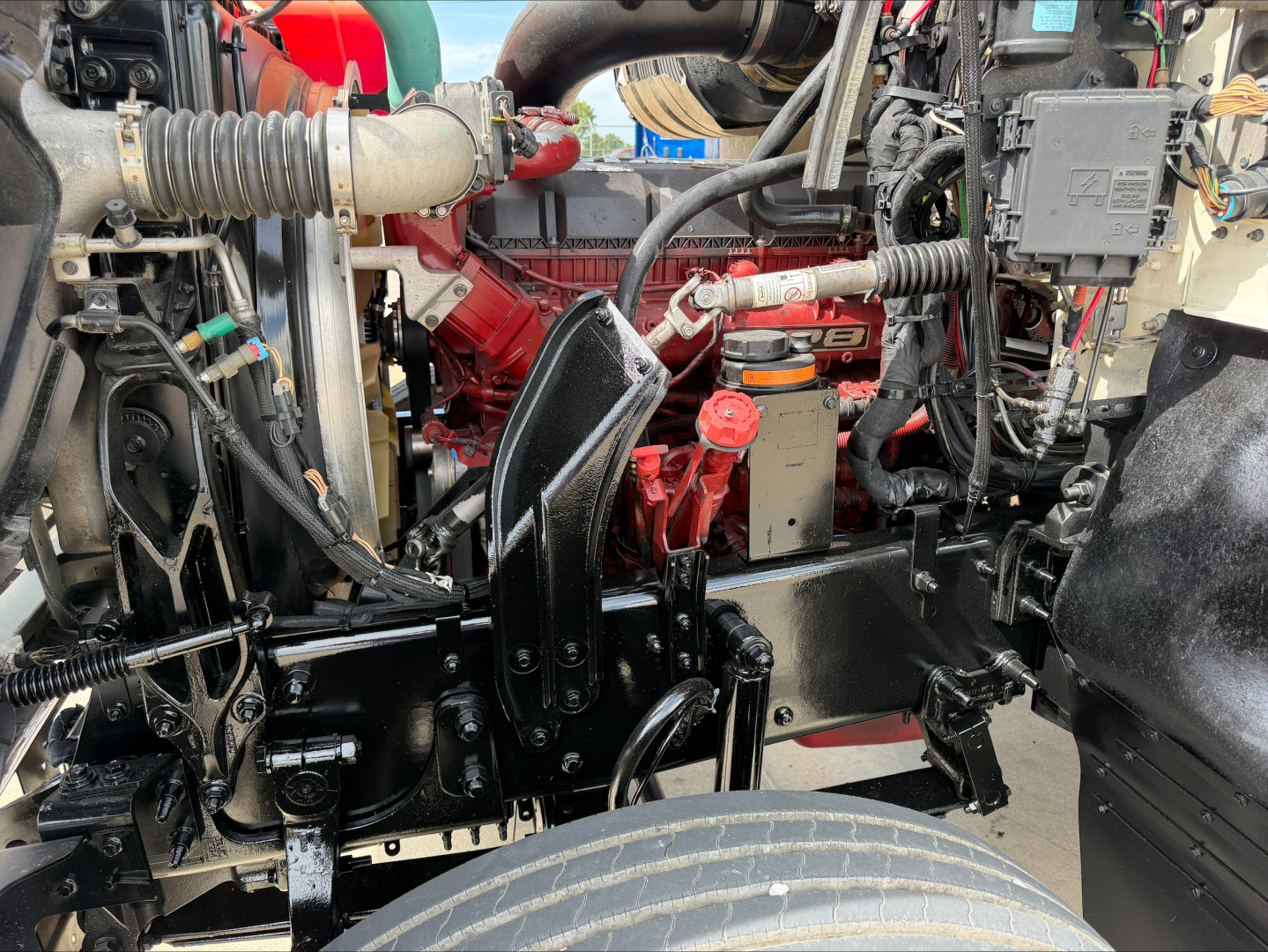 Mack PI64T engine bay showing red engine and surrounding components with black chassis and hoses.