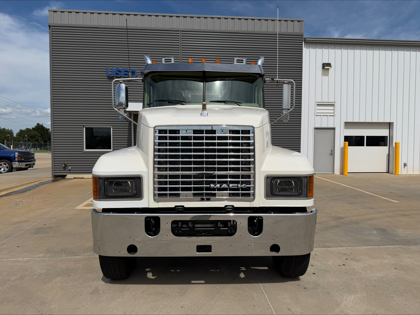Front view of a white 2019 Mack PI64T conventional daycab truck showing large grille, bumper, headlights, and Mack emblem