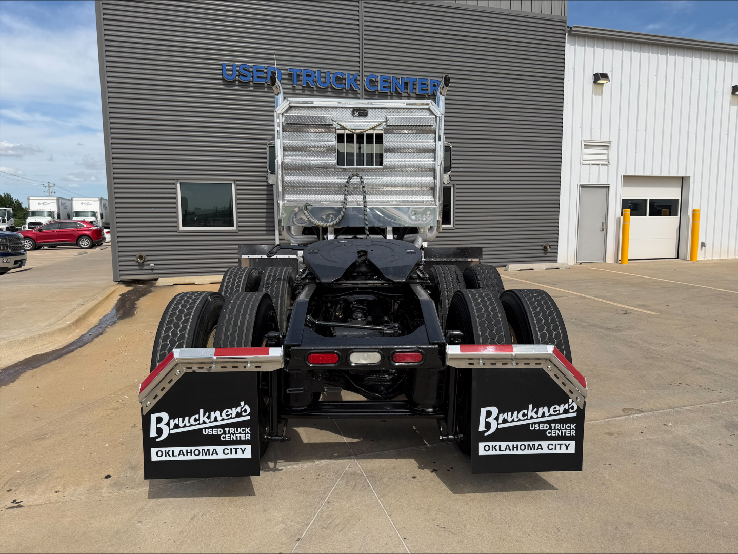 Rear view of 2019 Mack PI64T daycab tractor showing dual rear axles, mud flaps labeled Bruckner's Used Truck Center Oklahoma City, fifth wheel and chassis visible.