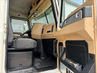 Cab interior of 2019 Mack PI64T daycab showing tan dashboard and driver seat with control panels.