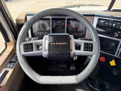 Mack PI64T truck cabin steering wheel view showing dashboard gauges and controls with Mack logo on wheel center.
