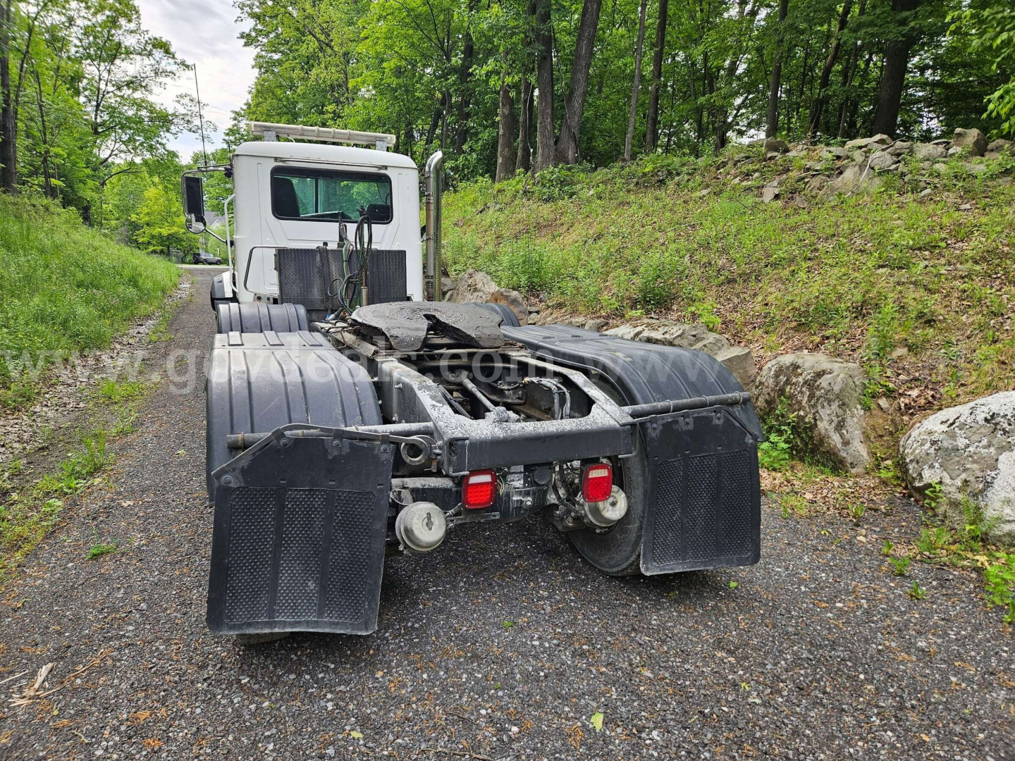 Mack GU813 rear view showing chassis and dual rear axles with mud flaps and hitch components.