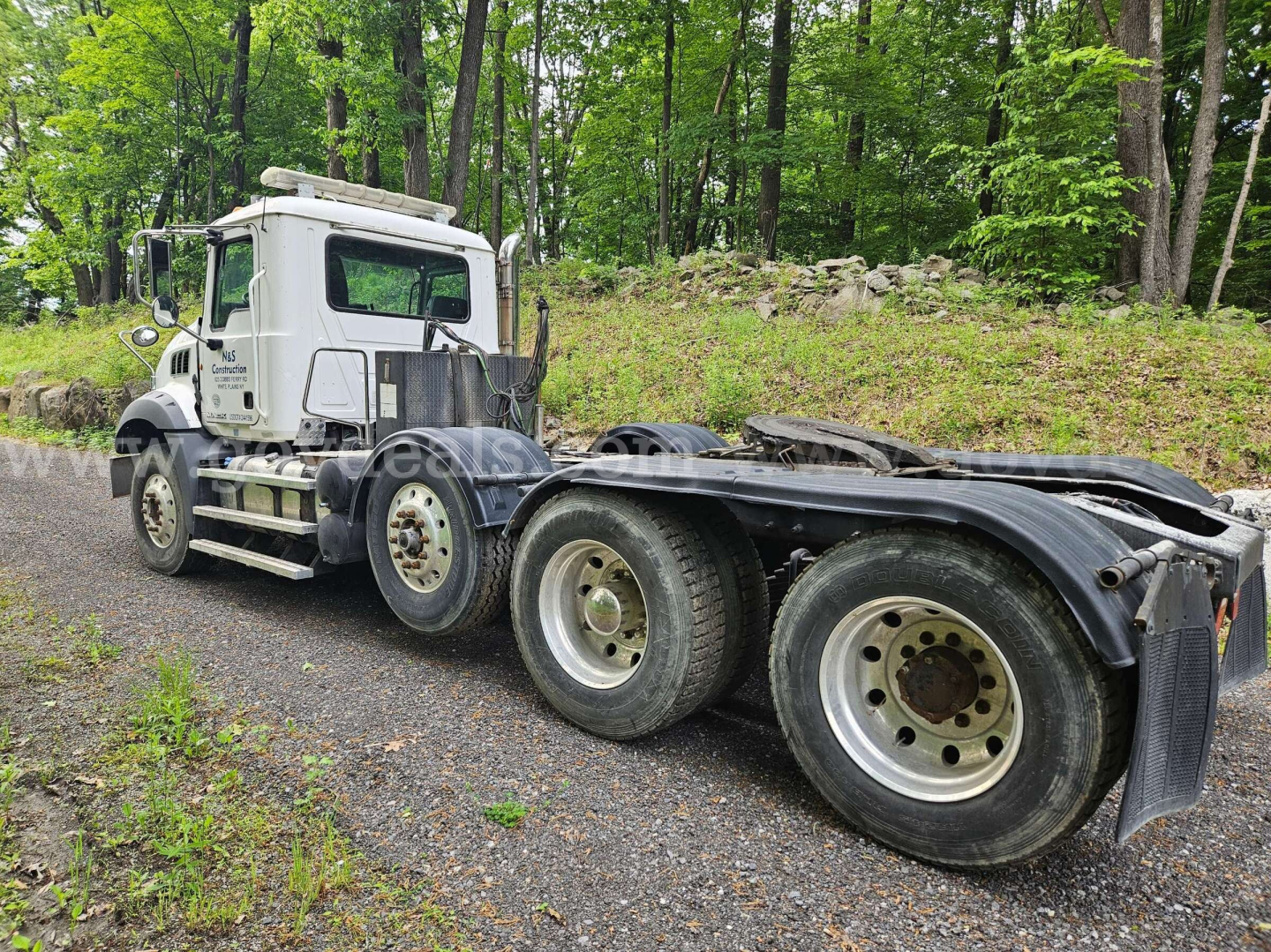 Truck chassis with cab and rear dual rear axles, white Mack GU813 cab, multiple wheels, no visible branding on wheels.