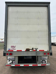  trailer rear view showing vertical roll-up door and taillights with bumper and reflective strips