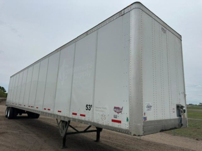Trailer side view showing 53' dry van with mid-frame landing gear and DOT markings on aluminum exterior.