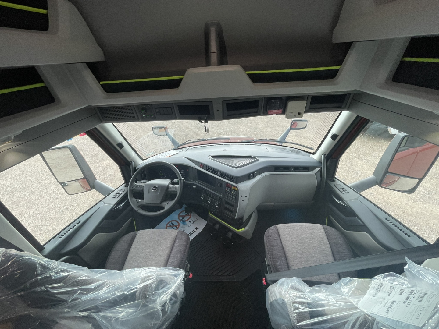Volvo VNL64T860 cab interior showing steering wheel, dashboard with controls, driver and passenger seats, and windshield view; no text visible on components.