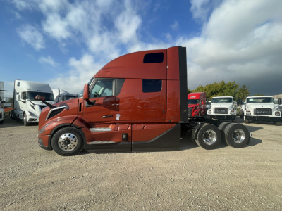 Volvo VNL64T860 sleeper tractor in side view showing cab and rear axle with orange paint and black accents.