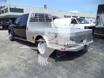 Ram 5500 truck with aluminum flatbed and toolbox seen from rear three-quarter view.