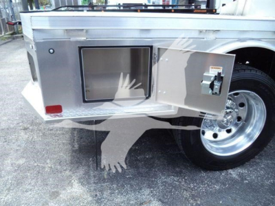 Ram 5500 utility bed side with open storage box and wheel, showing a rectangular aluminum storage compartment and latch.