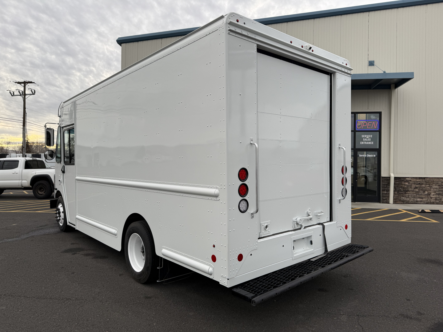 Harbinger S525 box truck rear view showing cargo doors and entry steps in white, side panel details, and wheel with black tire.