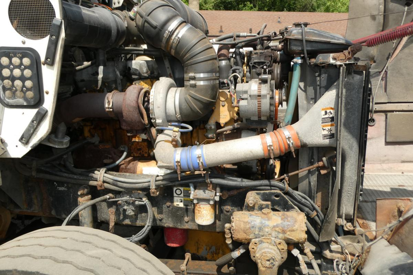 Kenworth T800 engine bay showing pipes, hoses, and radiator area with weathered components.