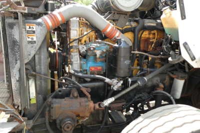 Kenworth T800 engine bay showing blue engine block with hoses, radiator, black oil filter, and surrounding mechanical components.