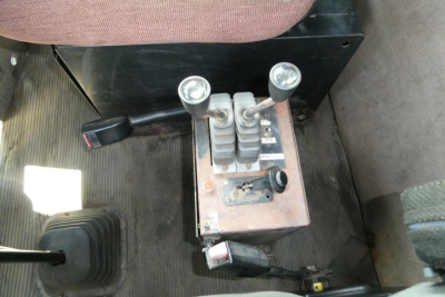 Kenworth T800 gear selector with two black shift levers and control pedals in cab interior.