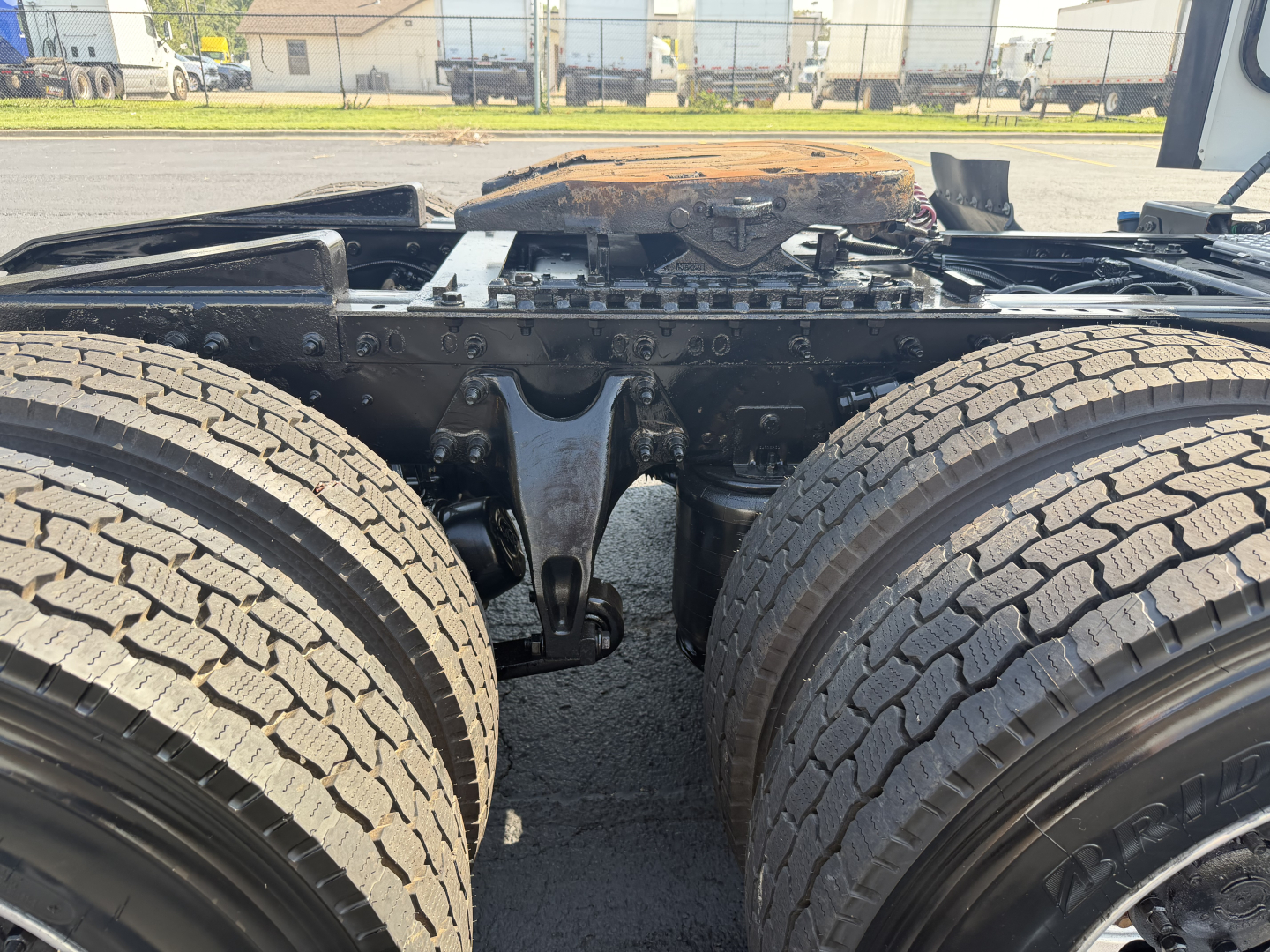 Truck chassis of a 2022 International LT625 showing rear axle, drive tires, and frame with engine area overhead; no visible fluid labels or decals.